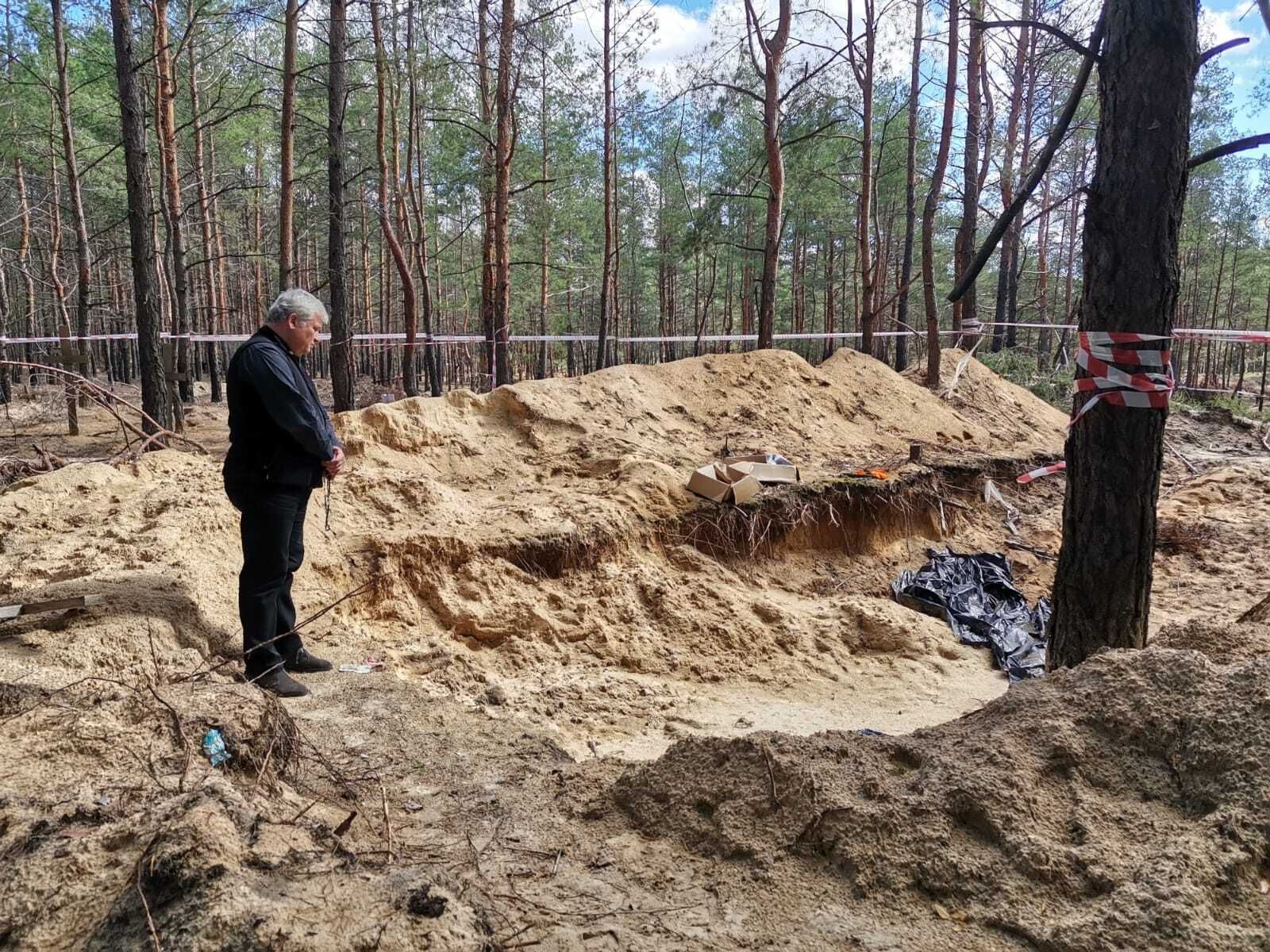 El cardenal Krajewski reza ante una fosa común en Ucrania