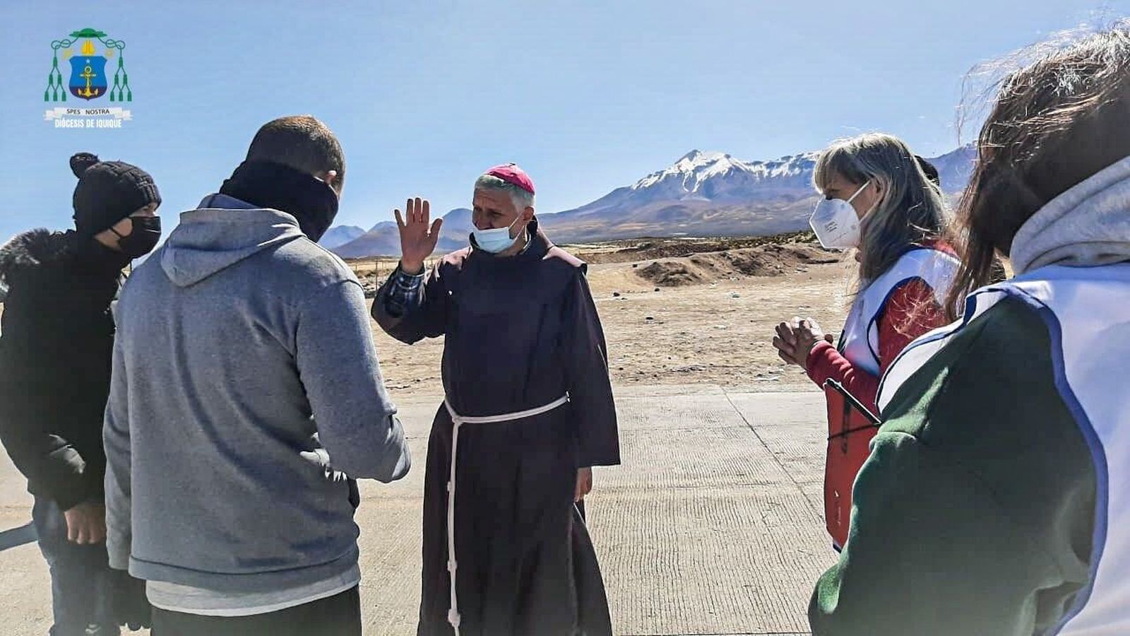 Mons Isauro Covili ora con voluntarios que atienden migrantes en la frontera chilena