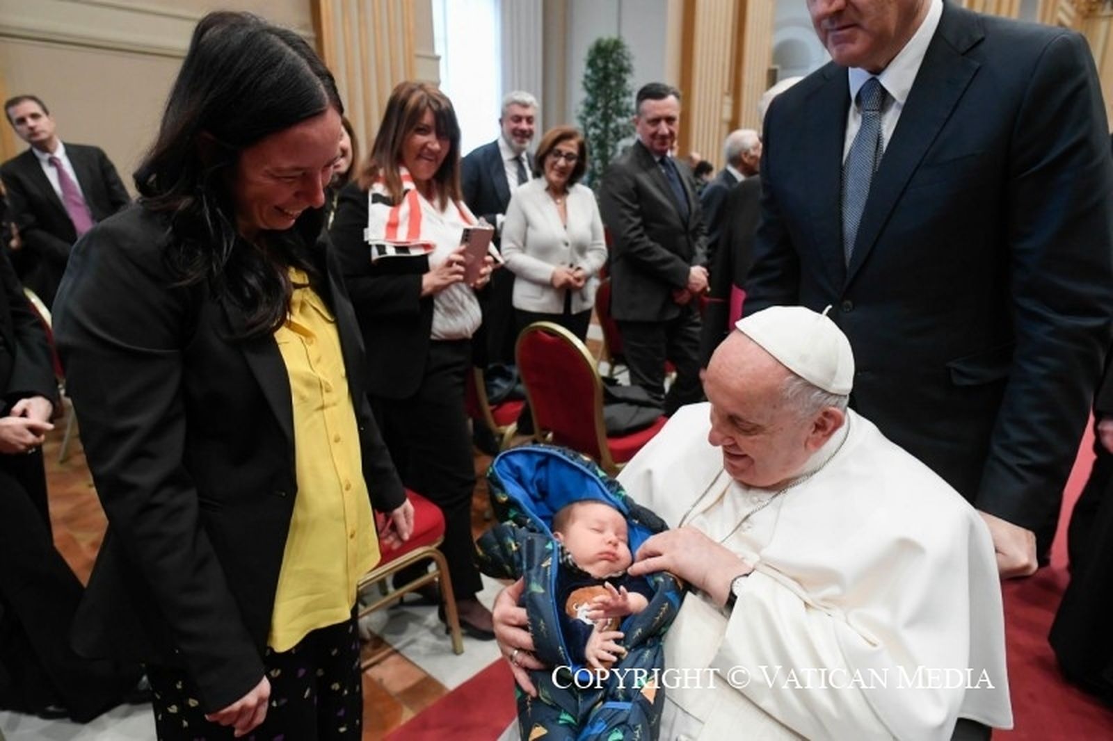 Francisco coge a un bebé en sus brazos
