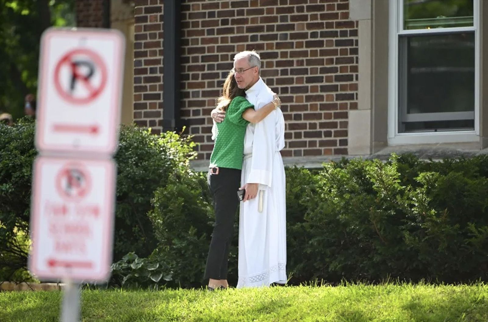 El P. Zehren consuela a una mujer a las puertas de la escuela