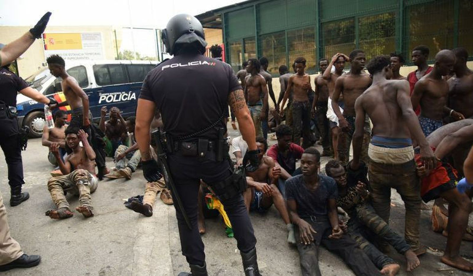 Migrantes y policías en la valla de Ceuta