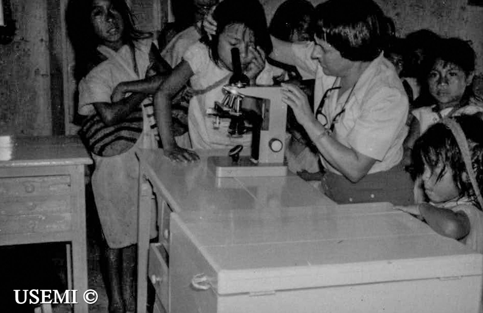 Sofía Toro le enseña a un grupo de niños cómo usar el microscopio