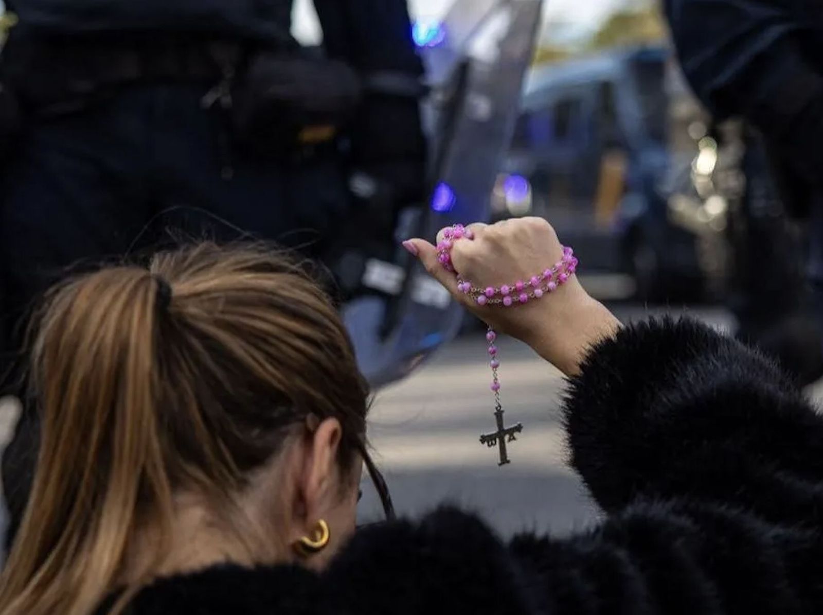 Una mujer con un rosario en las protestas contra el PSOE en la calle Ferraz