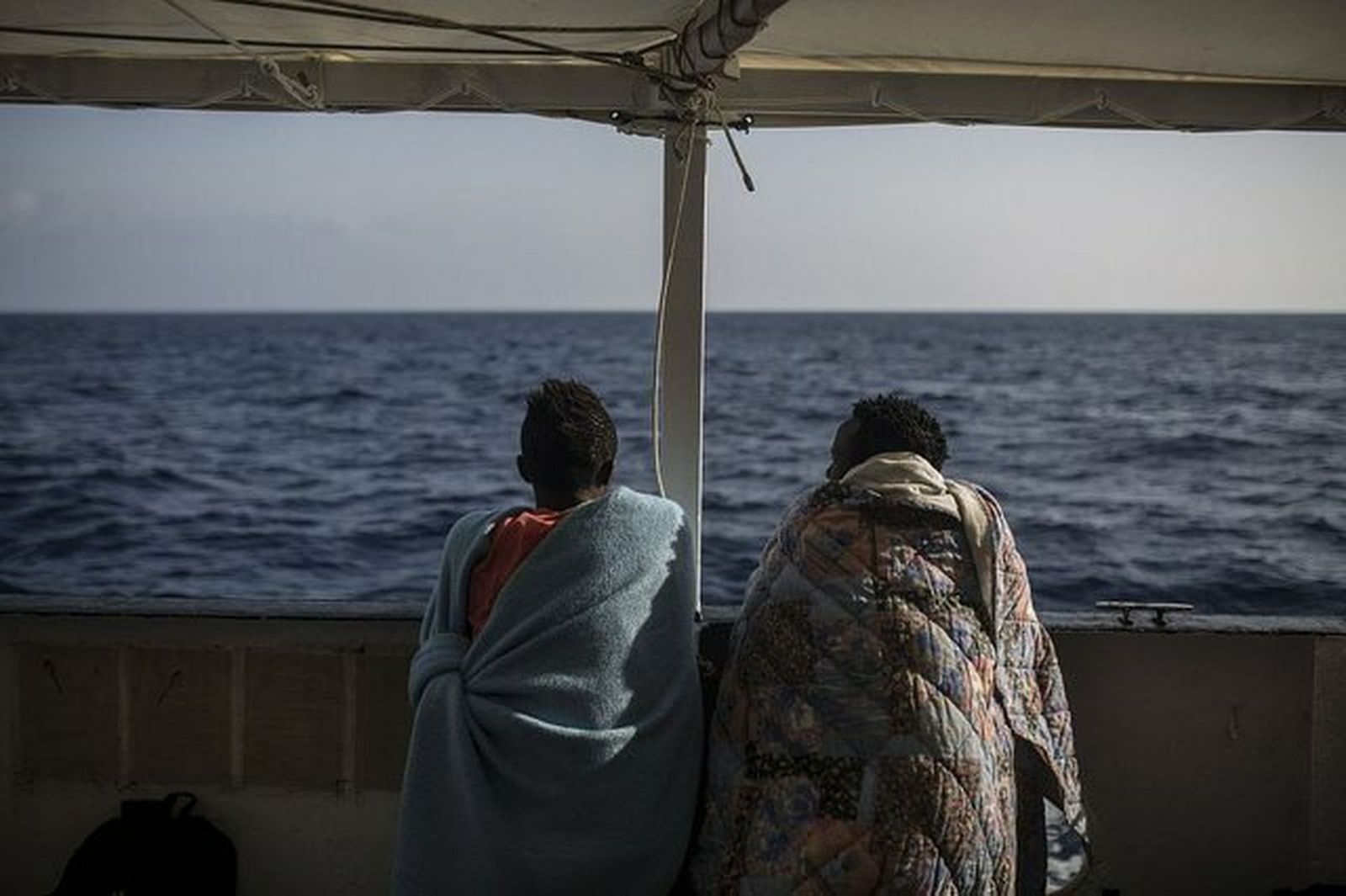 Dos migrantes hablan y observan el mar desde el Open Arms