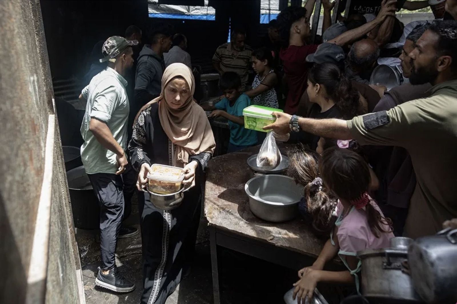 Una mujer recibe algo de comida en un comedor social en Gaza