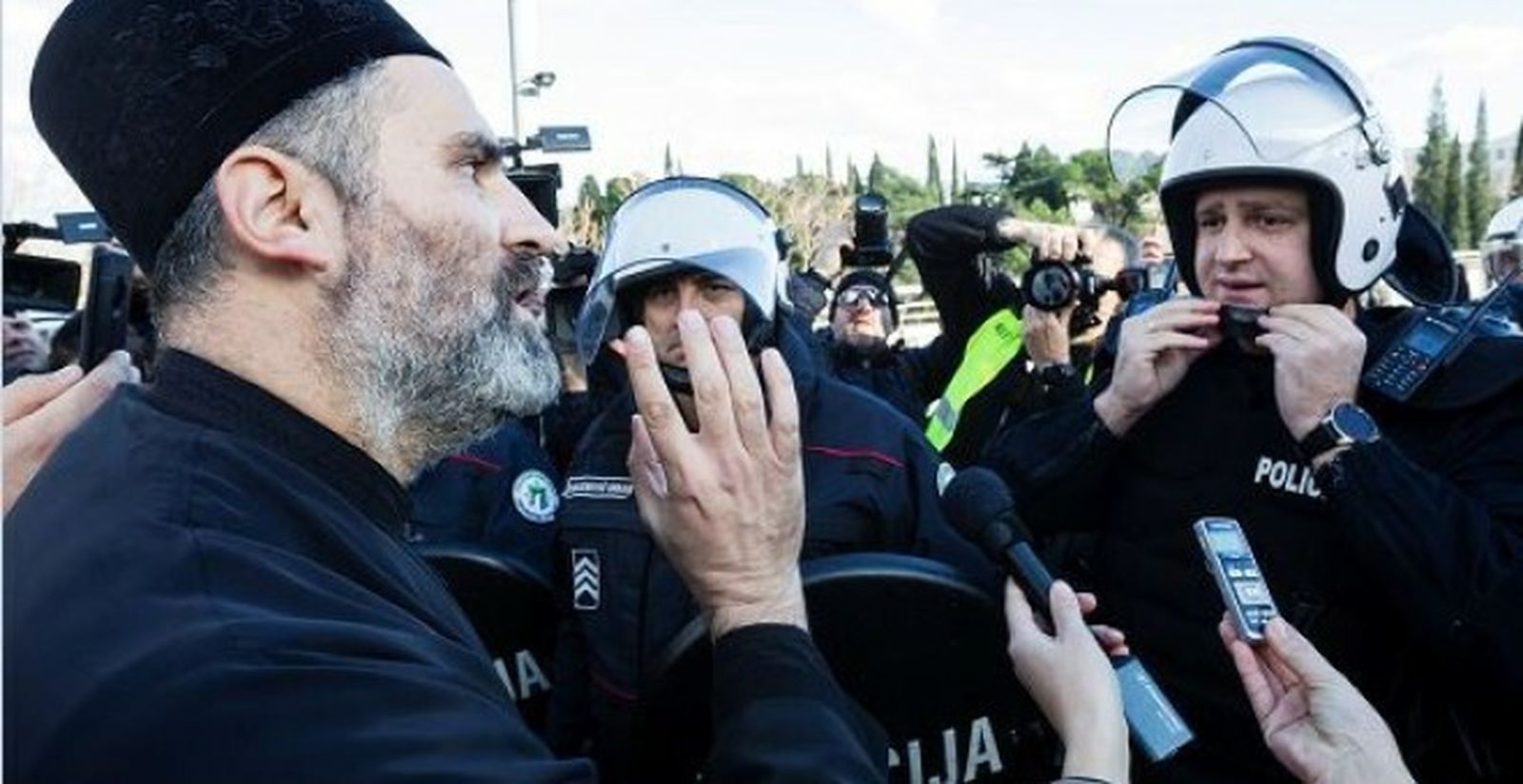 Un sacerdote de la Iglesia Ortodoxa Serbia habla con un policía antidisturbios en un puente cerca del parlamento, antes de votar un proyecto de ley sobre 'Libertades religiosas y derechos legales de las organizaciones religiosas' en Podgorica